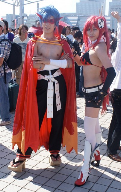 A woman with red hair and a man with blue hair pose in highly revealing costumes in the cosplay arena at Comic Market (Comiket) at Tokyo Big Sight