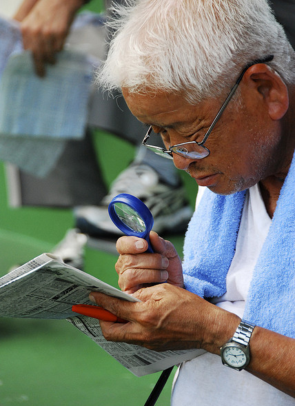 A man carefully studying a newspaper at a keirin stadium