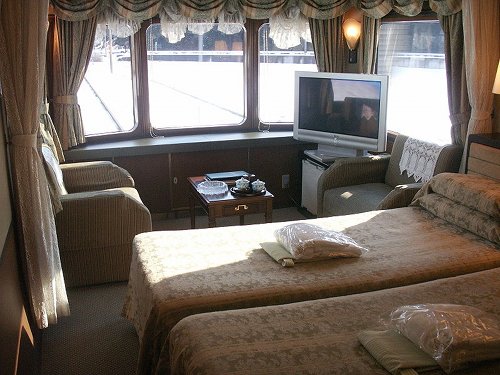 The suite at the back of the Twilight Express, with beds, a widescreen TV, and a view out the back of the train
