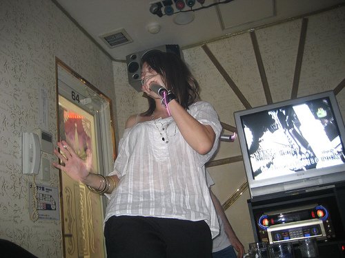A woman singing in a karaoke box