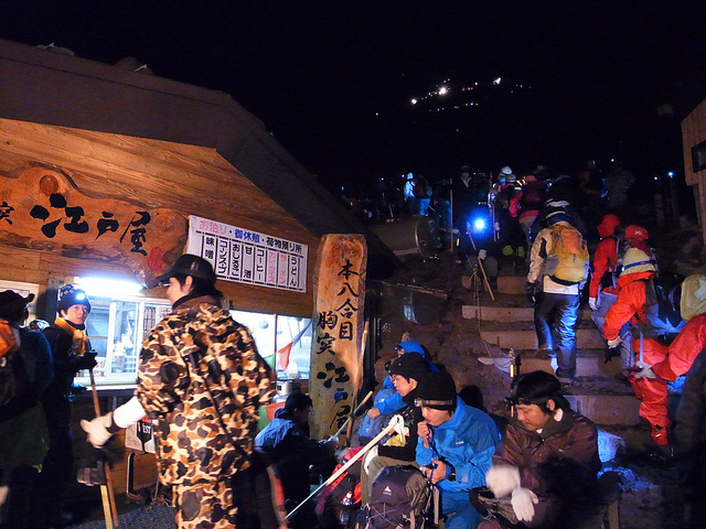 Climbers passing a hut selling drinks and noodles on Mount Fuji at night